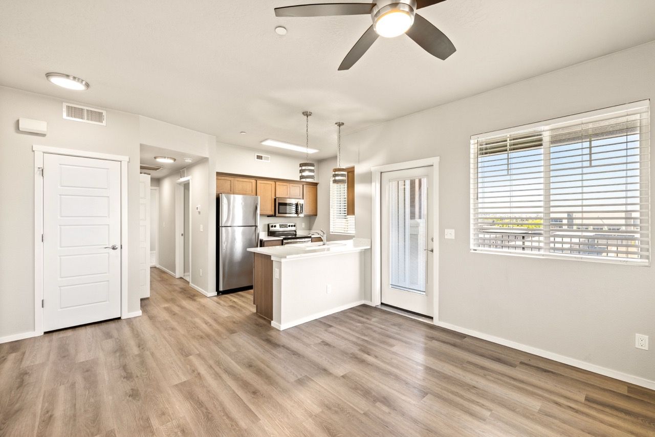 Open-concept living area with kitchen, island, stainless steel appliances, and a balcony door.