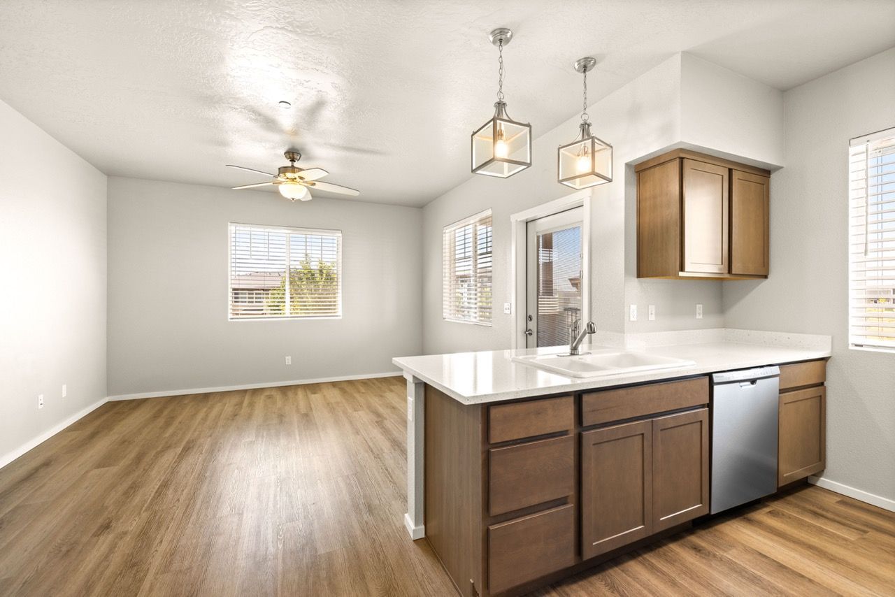 Open-concept kitchen with island, pendant lights, wood cabinets, and stainless-steel appliances.