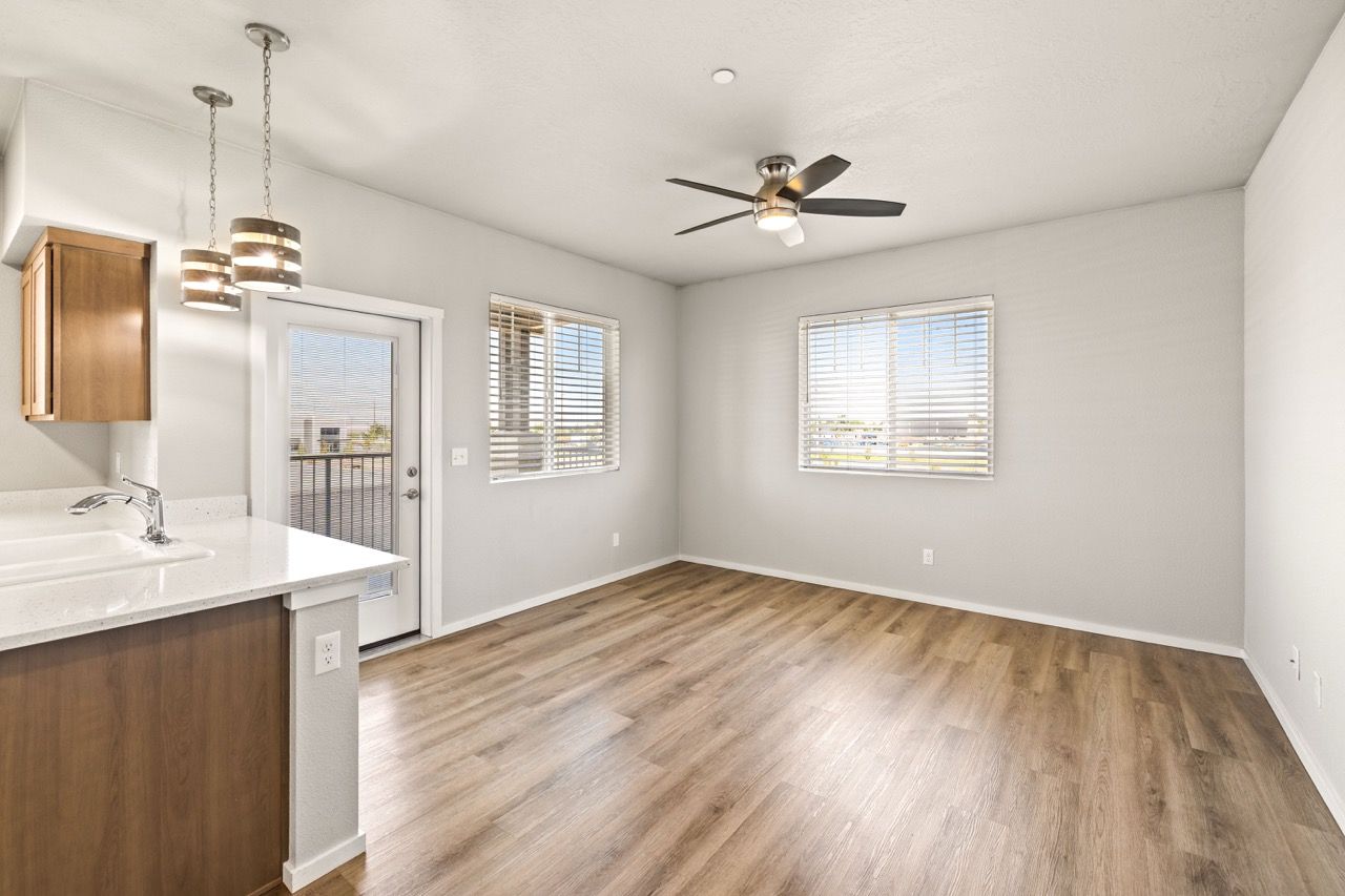 Bright open-concept apartment living area with a kitchen counter, sink, and two windows.
