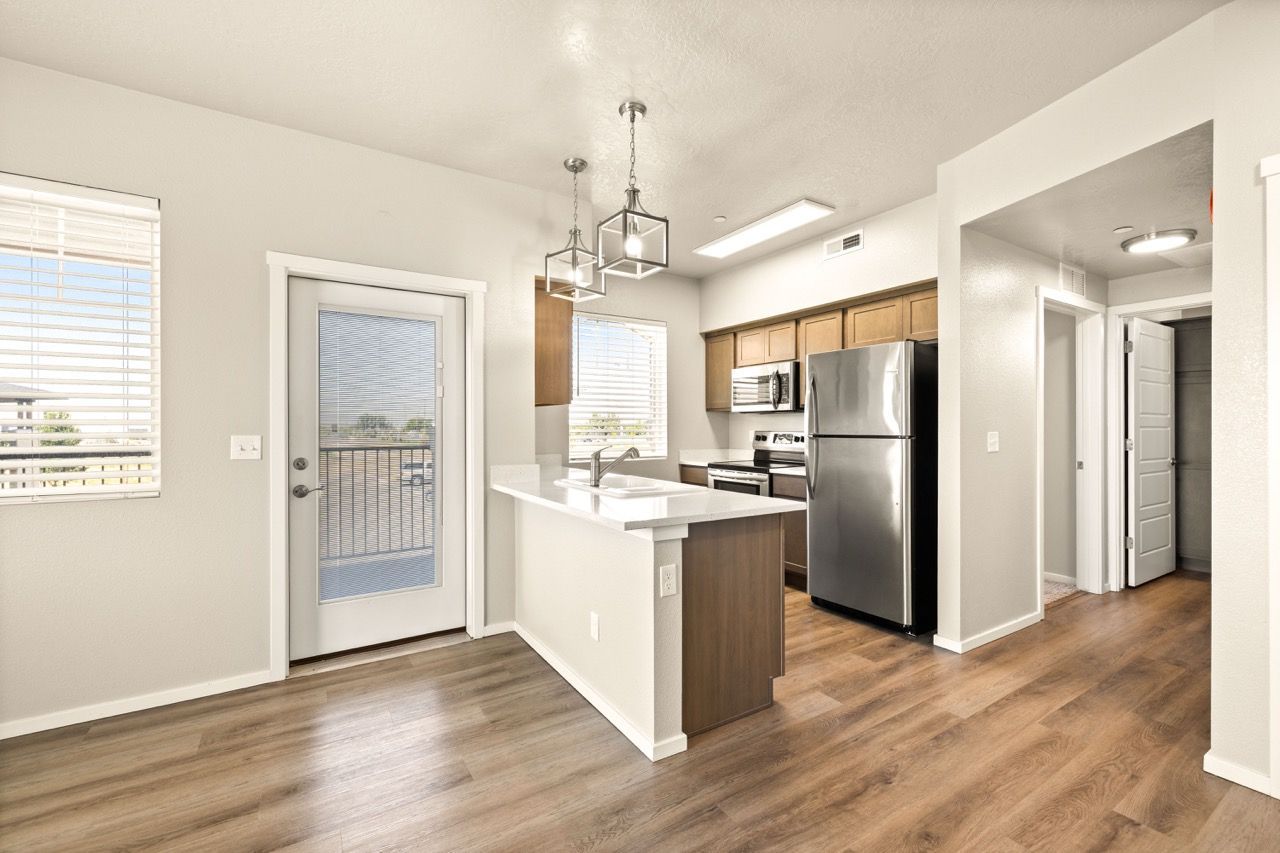 Open-concept kitchen in an apartment with stainless steel appliances, island, and wood flooring.
