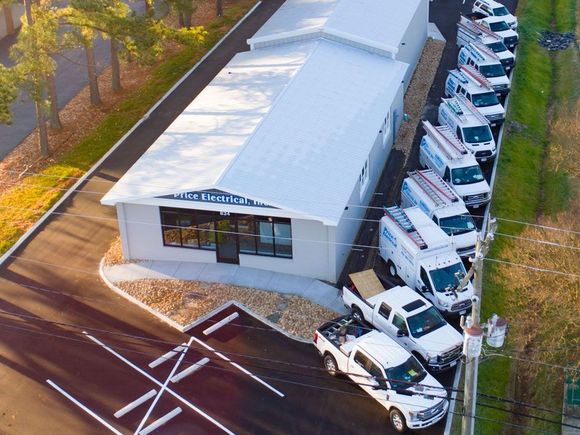 A row of white vans are parked in front of the Price Electrical building