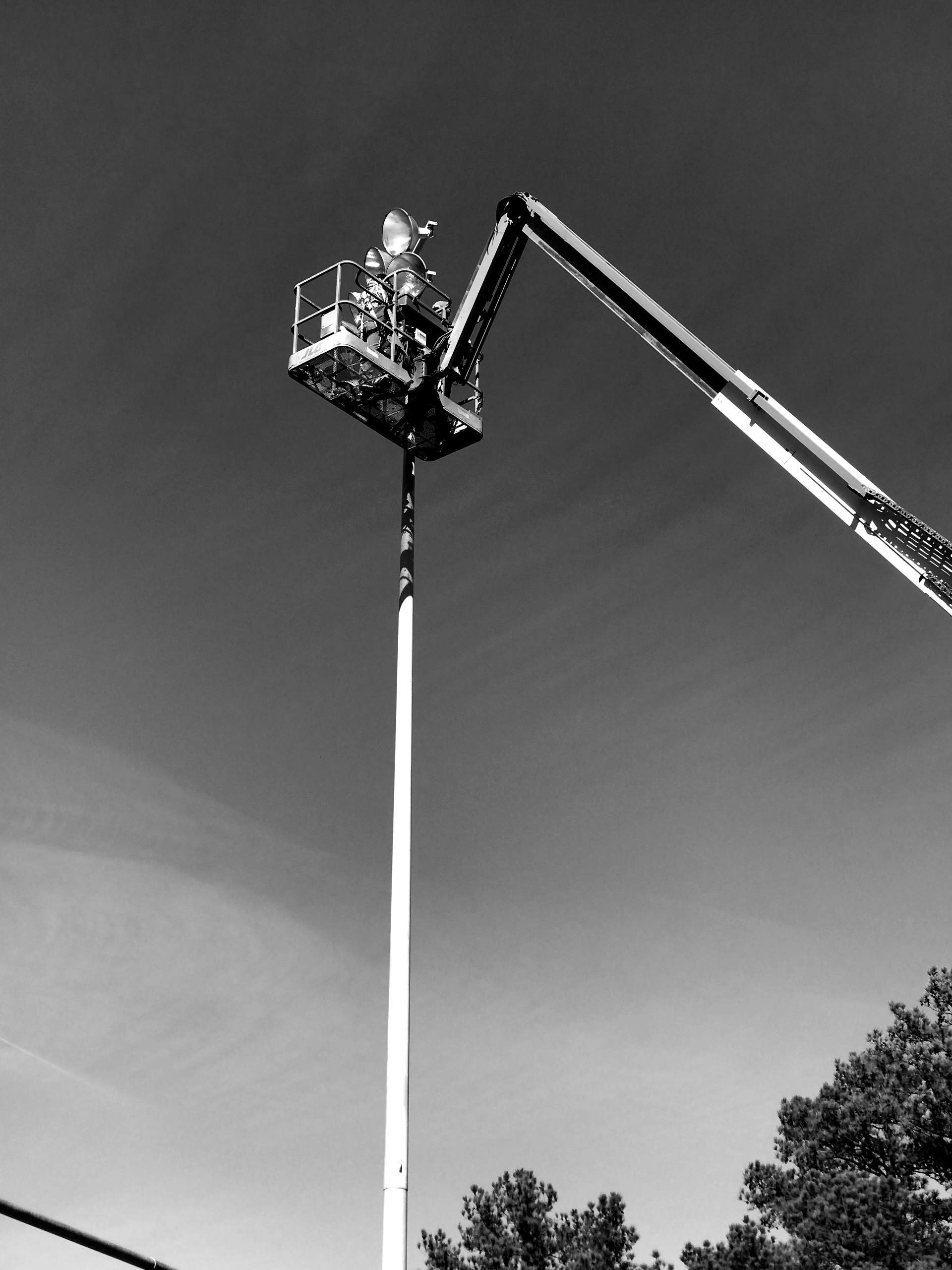 A black and white photo of a crane lifting a pole