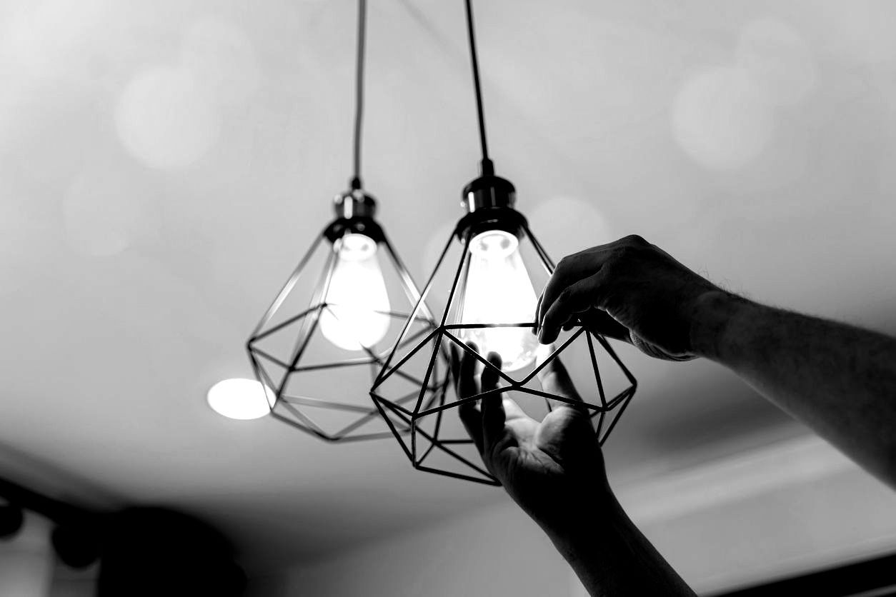 A person is changing a light bulb in a black and white photo.