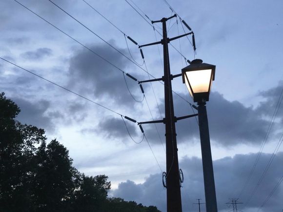 A street light is lit up in front of a cloudy sky