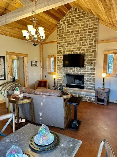 Rustic living room with stone fireplace, TV, and exposed wood beams.