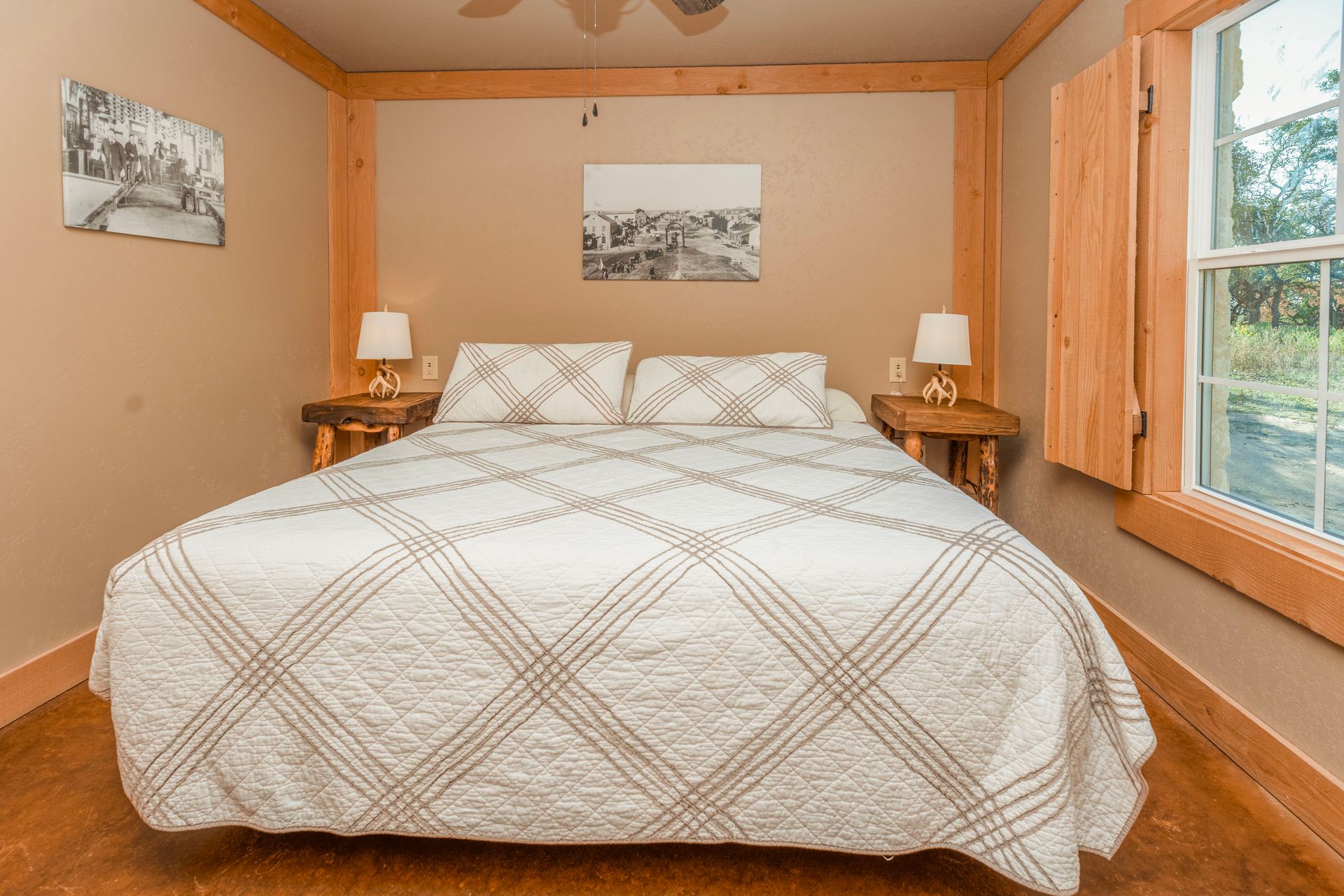 Bedroom with a bed, nightstands, artwork, and a window with wooden trim.