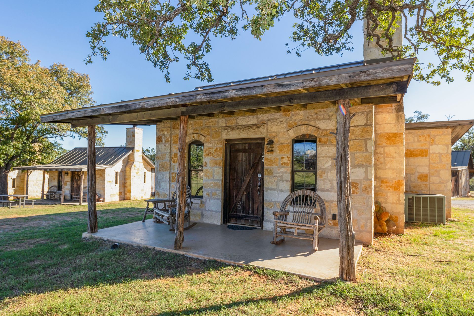 Stone cottage with wooden porch and rocking chair.