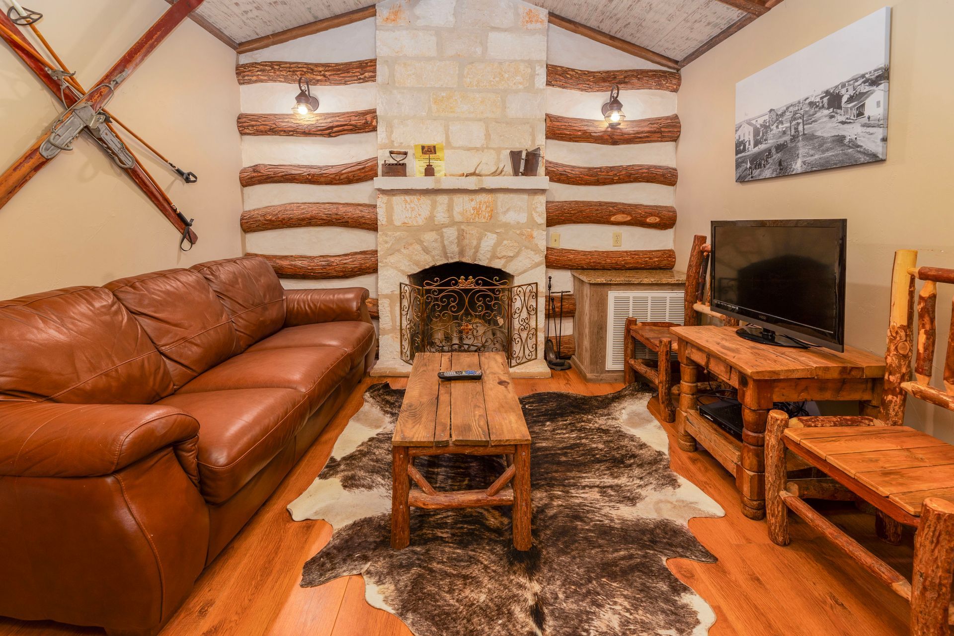 Rustic living room with leather sofa, fireplace, TV, and log accents.