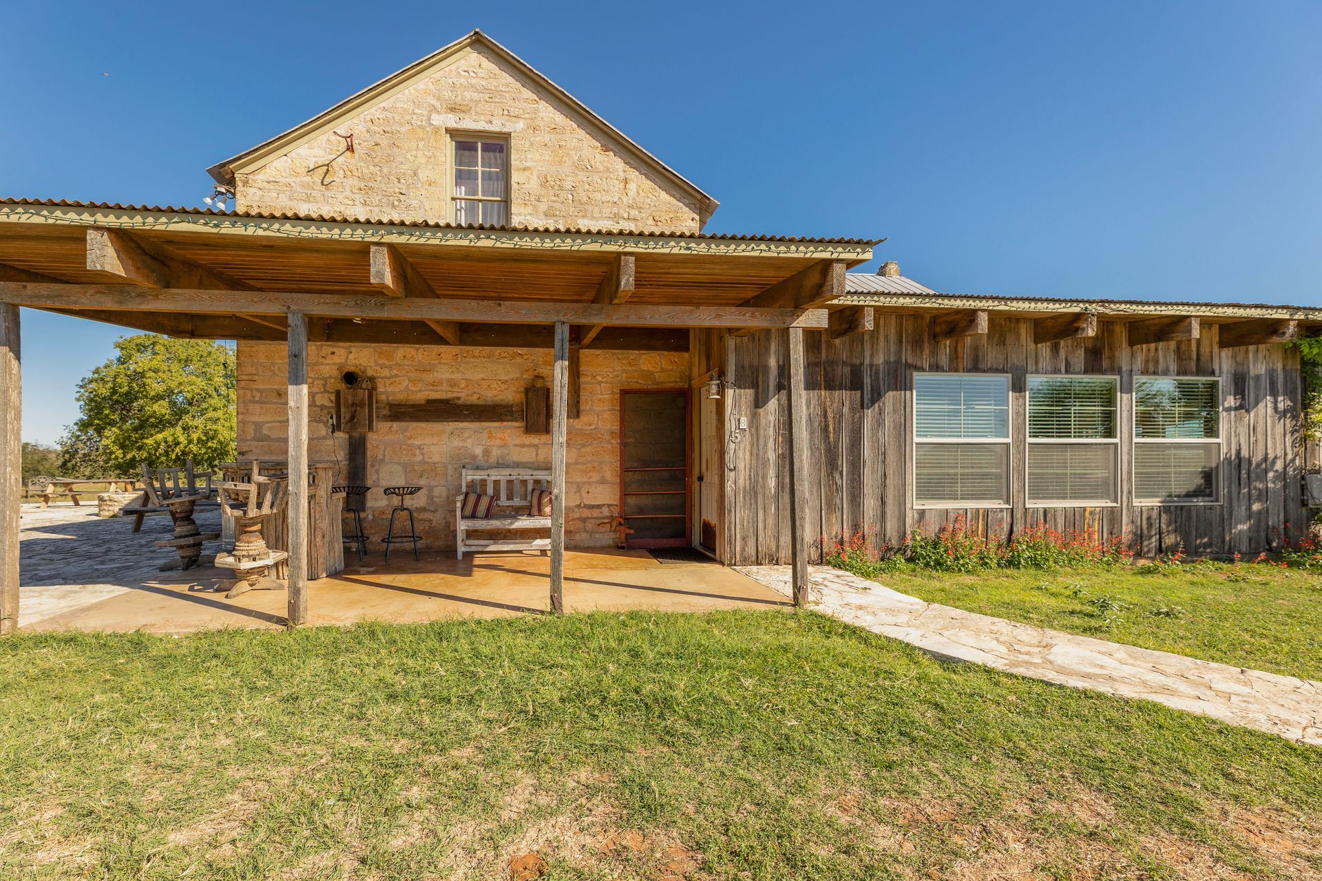 Rustic stone and wood house with porch, blue sky.