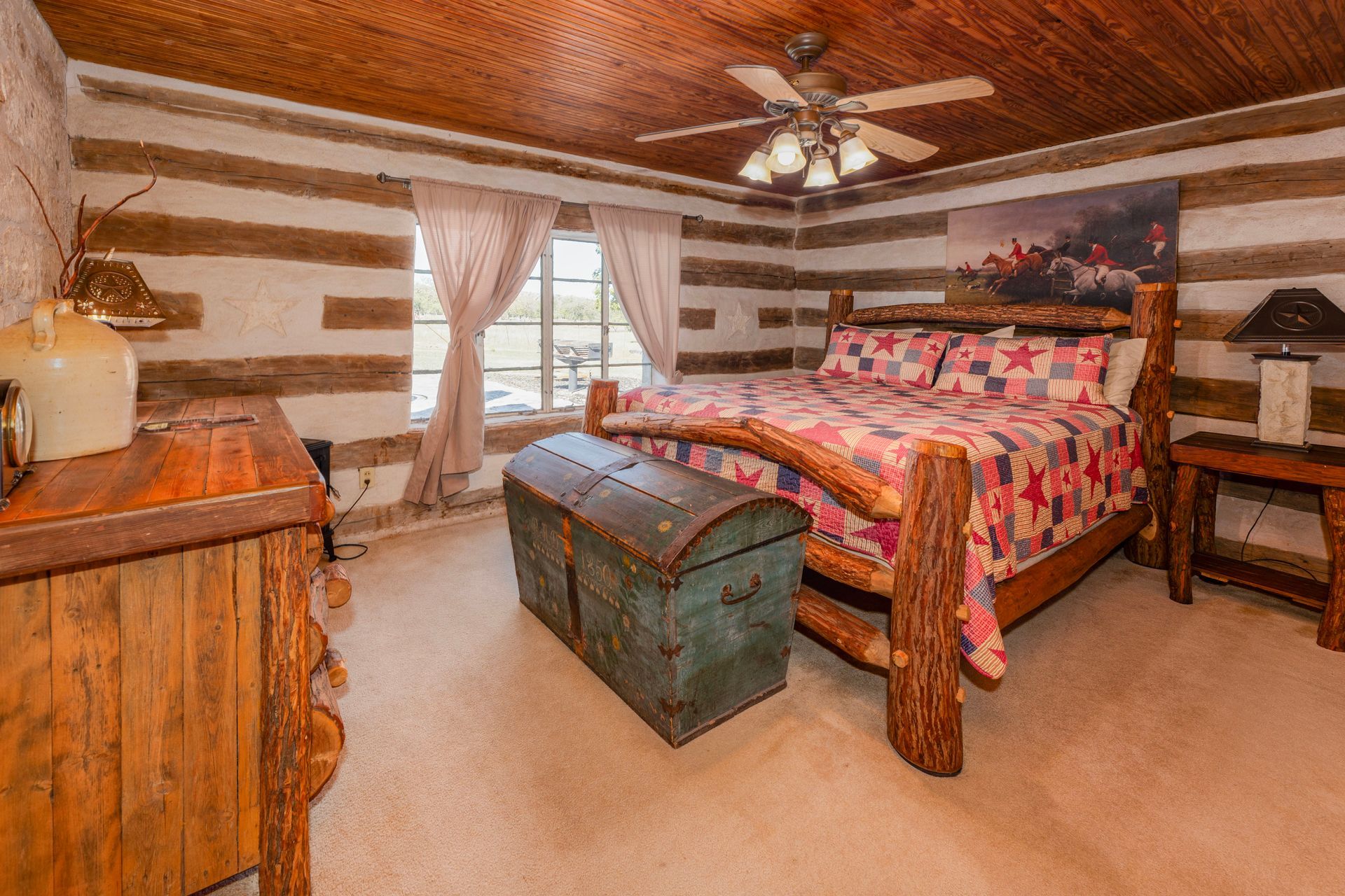 Rustic bedroom with log walls, wooden furniture, and a quilt-covered bed.