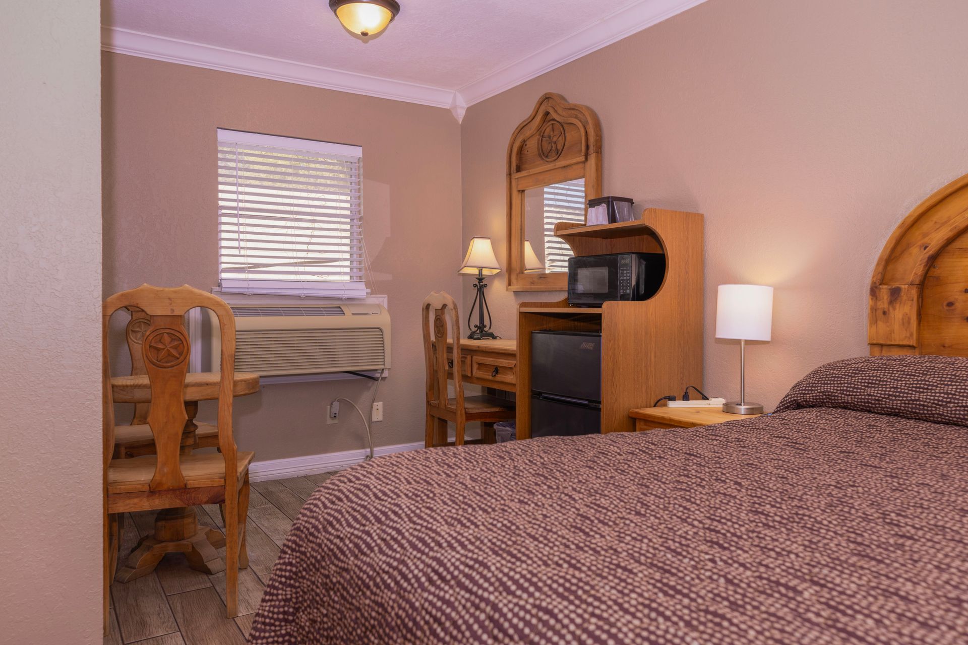 Bedroom with a bed, desk, and window; neutral tones.