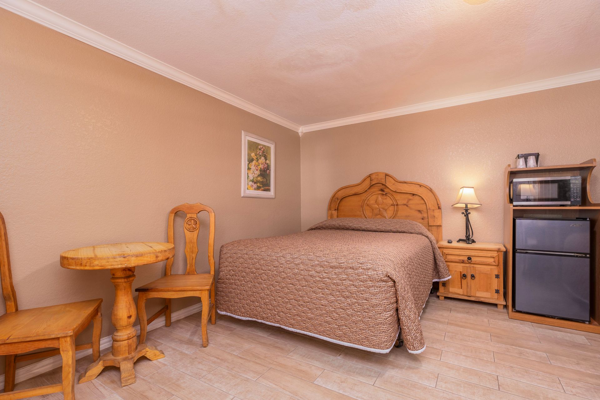 Hotel room with a bed, small table, chairs, and microwave.