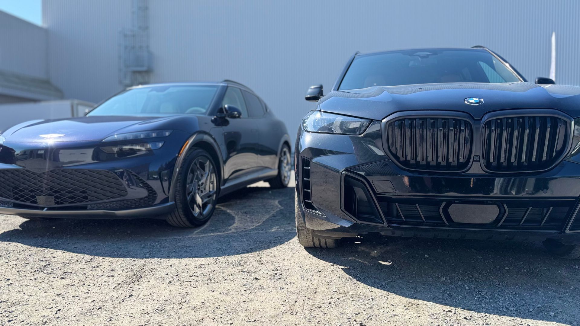 Deux voitures bleu foncé garées côte à côte à l'extérieur : un coupé et un gros SUV.