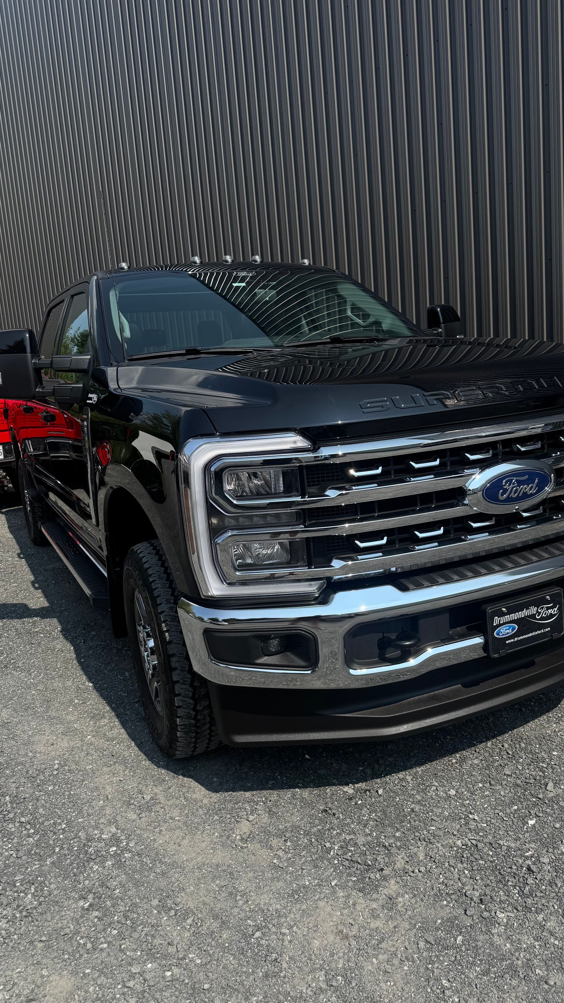 Camionnette Ford noire garée devant un mur texturé.