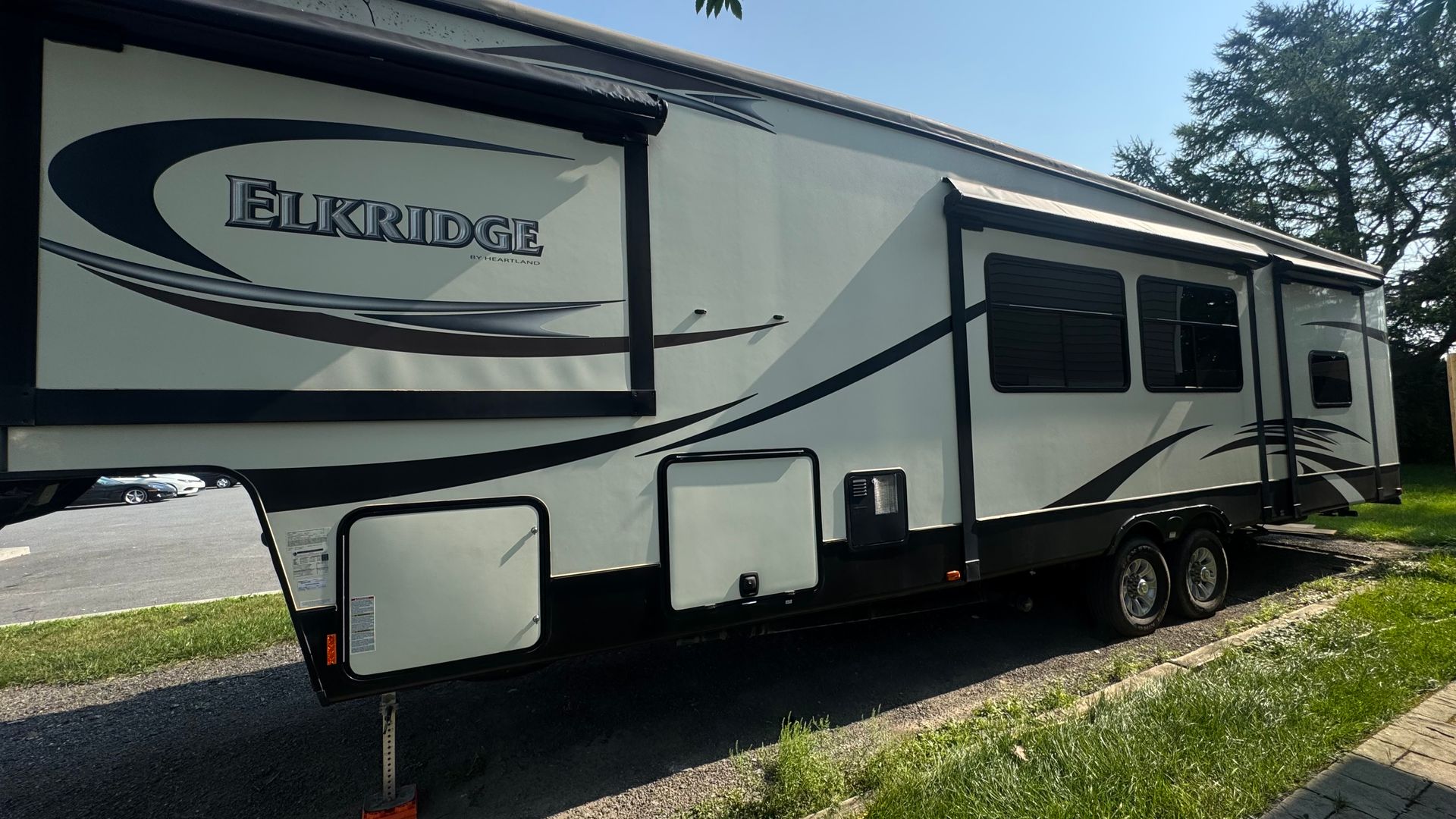 Un grand véhicule récréatif (VR) blanc et noir stationné sur l'herbe à côté d'un bâtiment.