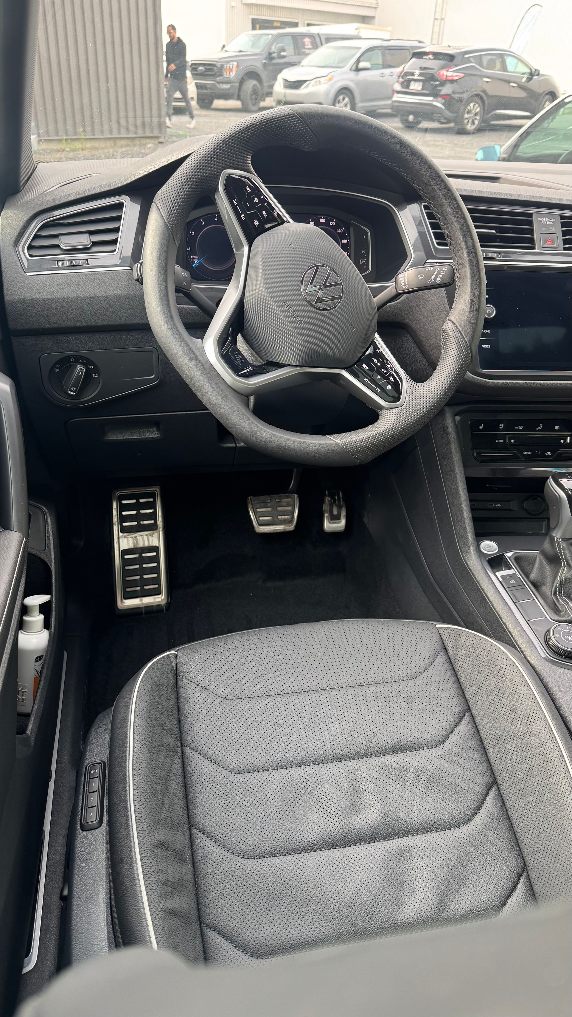 Vue intérieure du siège conducteur, du volant et du tableau de bord d'une voiture noire.