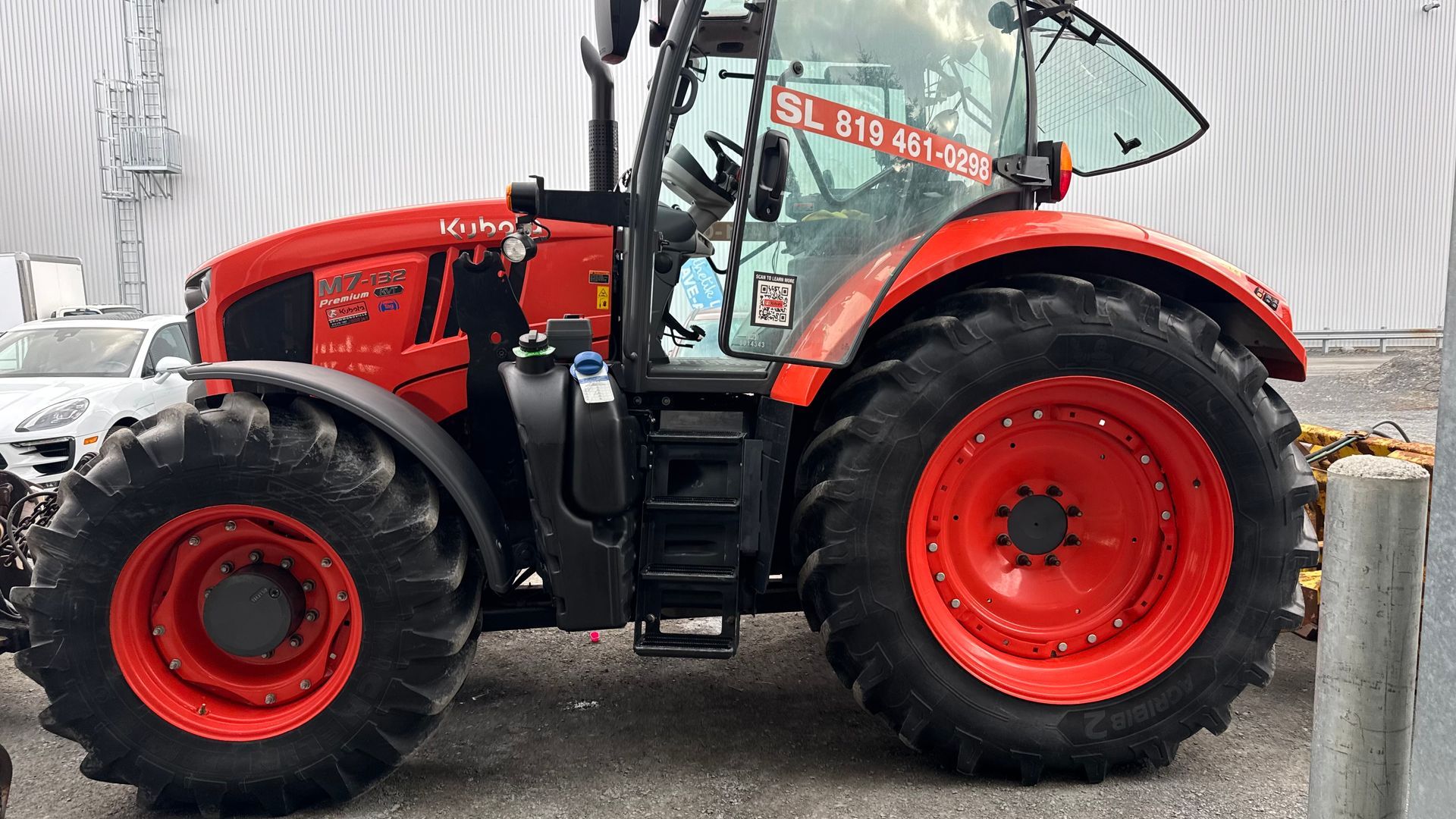 Tracteur rouge avec pneus noirs garé à l'extérieur.