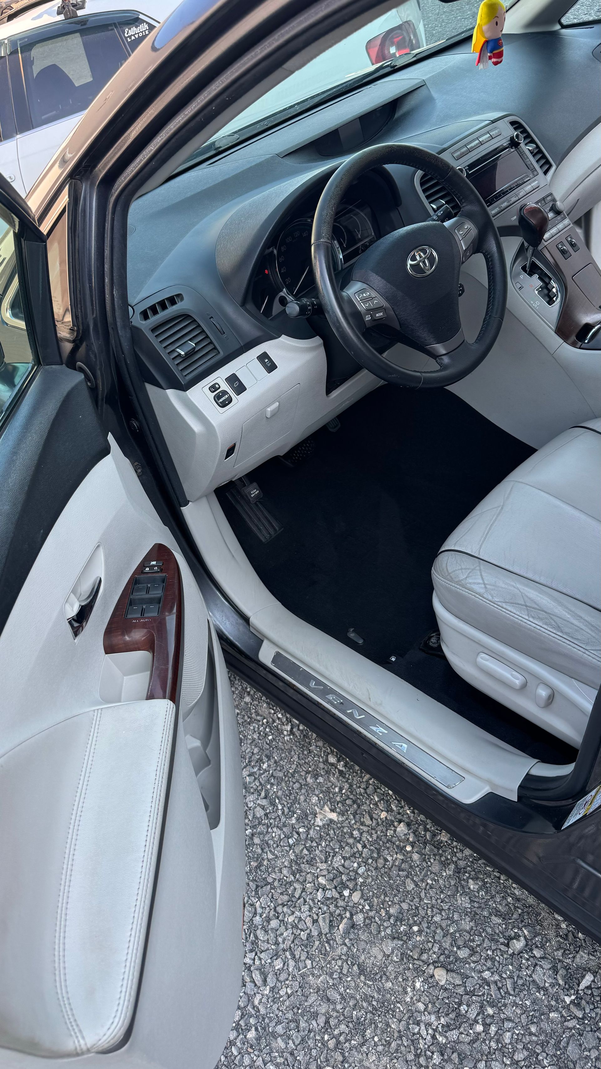 Intérieur d'une voiture grise ; la porte ouverte révèle un volant, un tableau de bord et des sièges, le tout en gris clair.