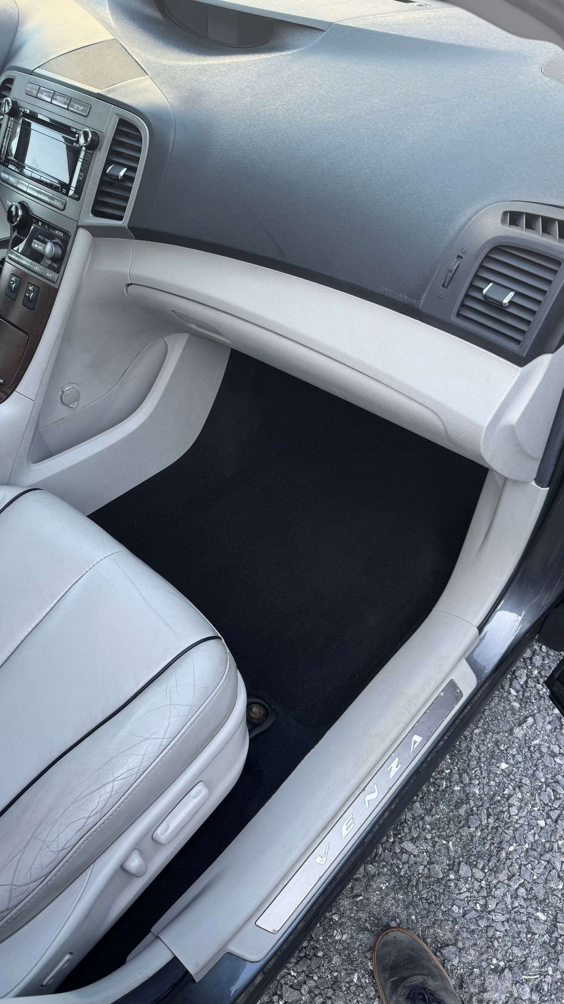 Intérieur d'une voiture de couleur claire avec des sièges gris et un tapis de sol noir.