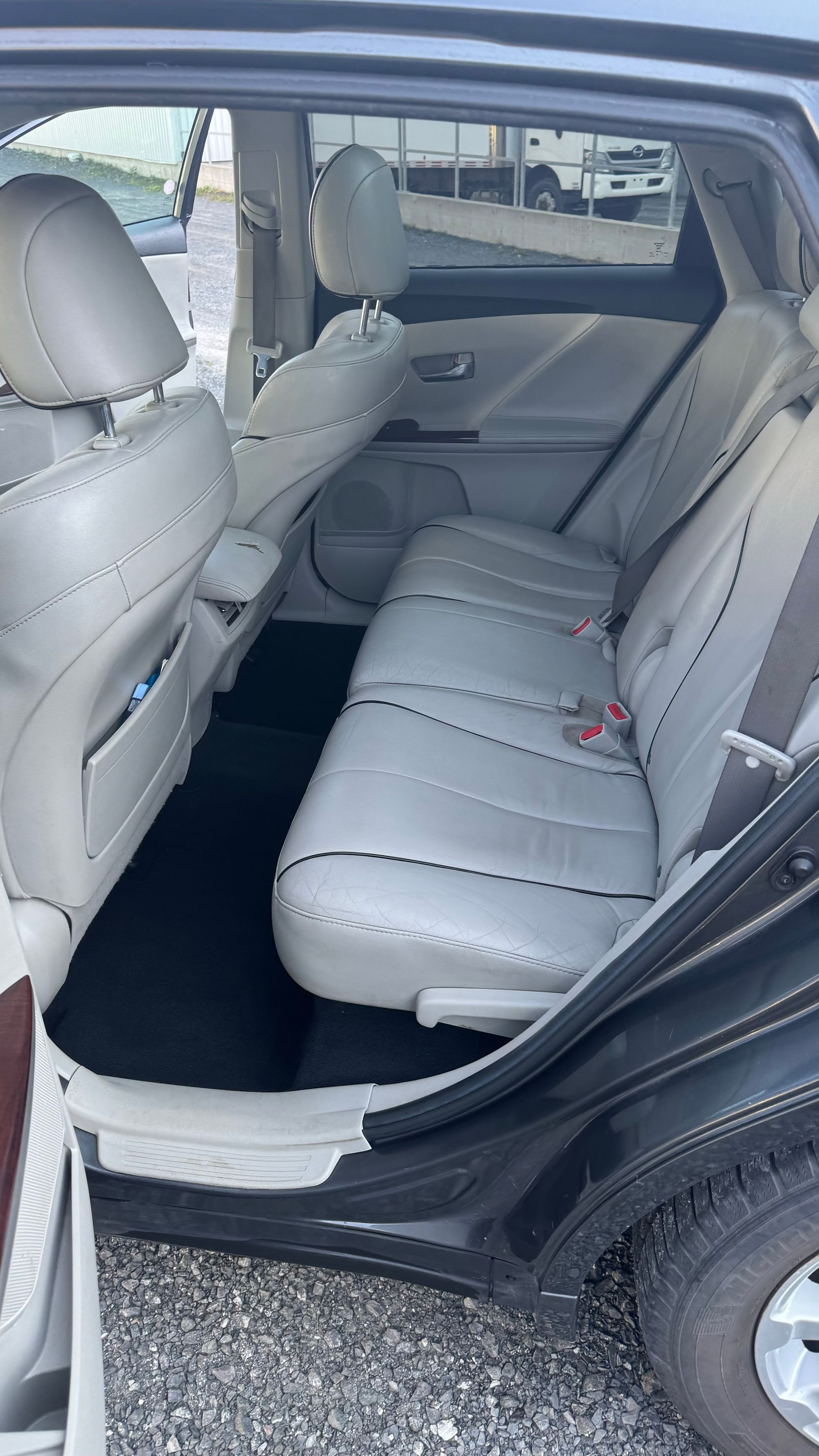 Vue intérieure d'une voiture grise avec sièges gris clair, tapis de sol noirs.