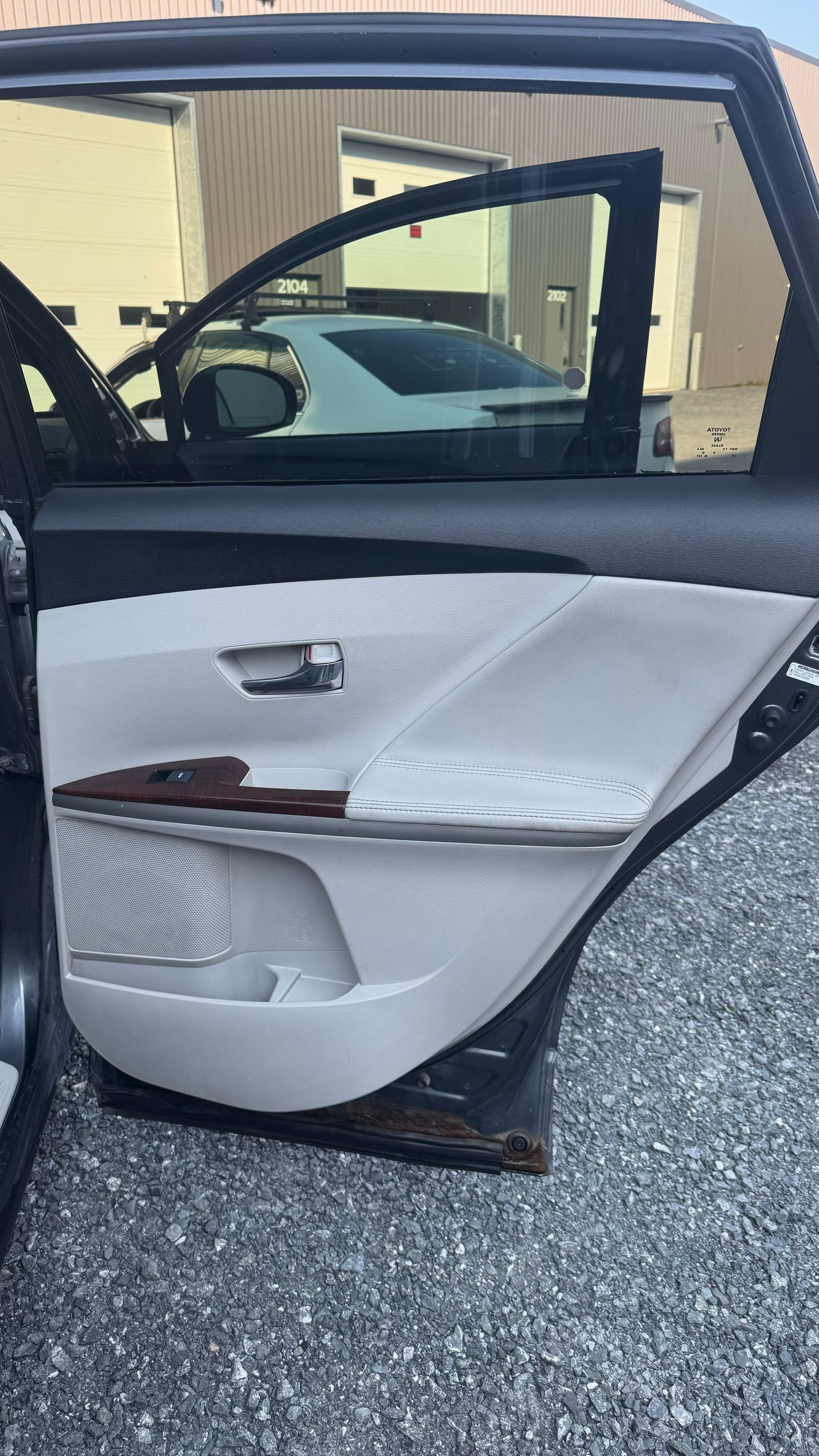 Ouvrez la porte de la voiture révélant un panneau intérieur de couleur claire avec des garnitures en bois et une petite poche de rangement.