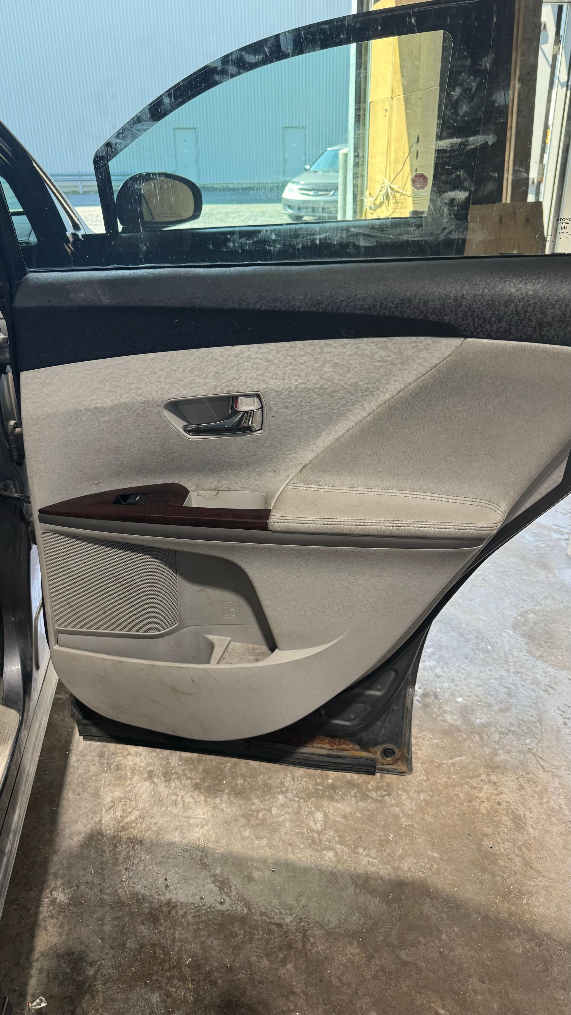 Intérieur de porte de voiture, gris clair avec garniture en bois et haut-parleur.