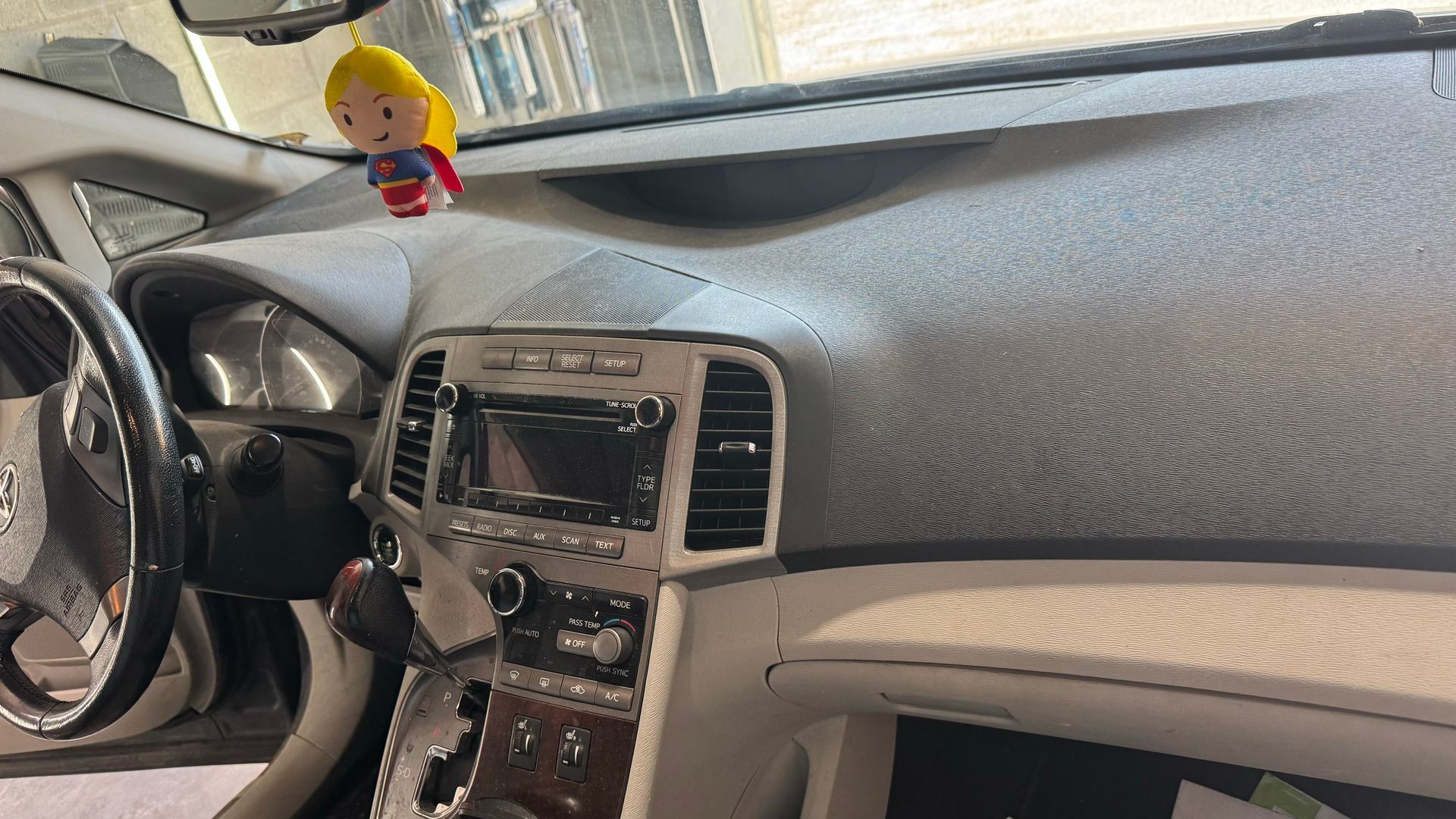 Intérieur de voiture avec un tableau de bord détaillé et une petite poupée blonde.