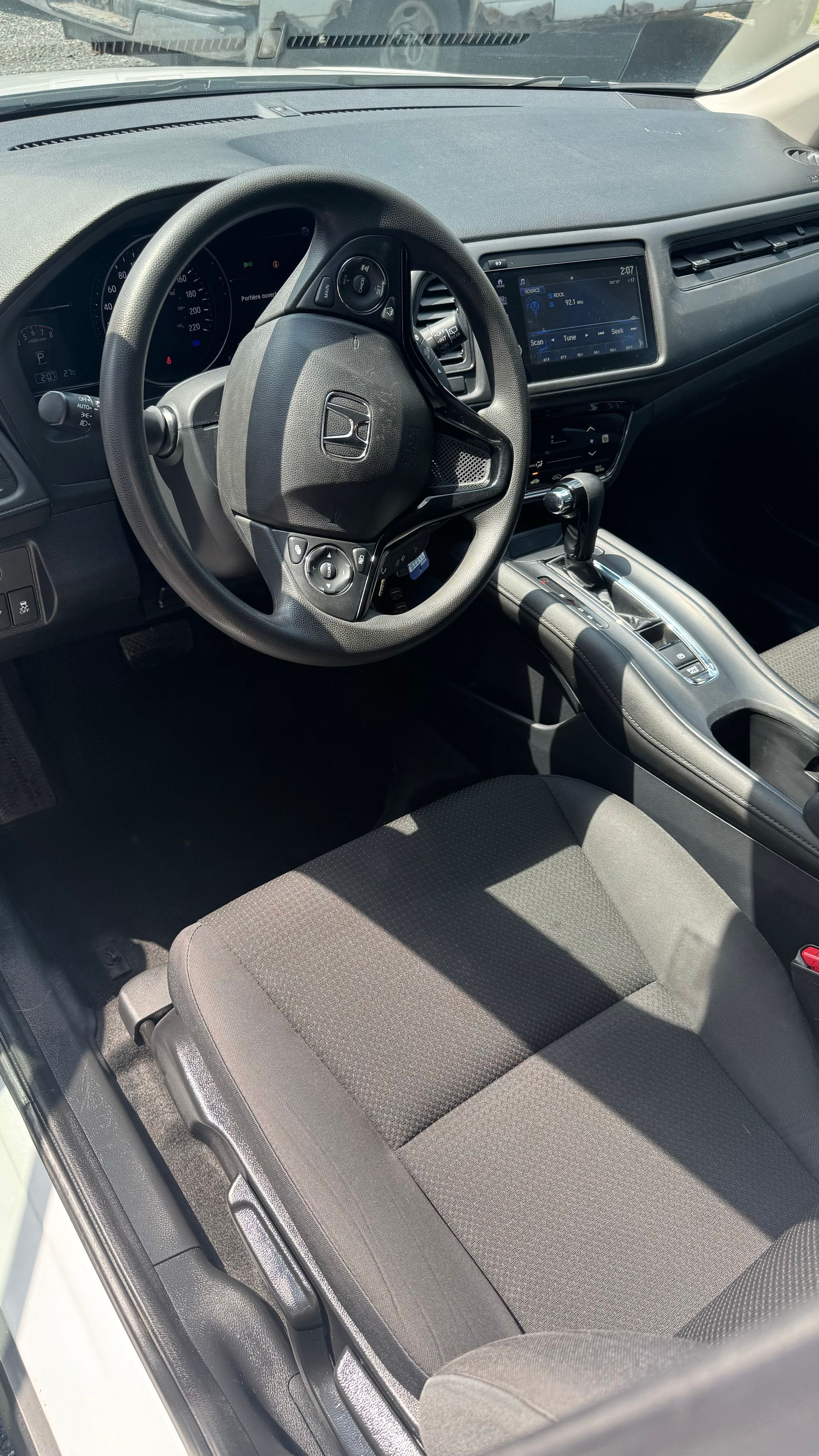 Intérieur d'un Honda HR-V noir. Volant, tableau de bord et sièges noirs. Console avec levier de vitesse.