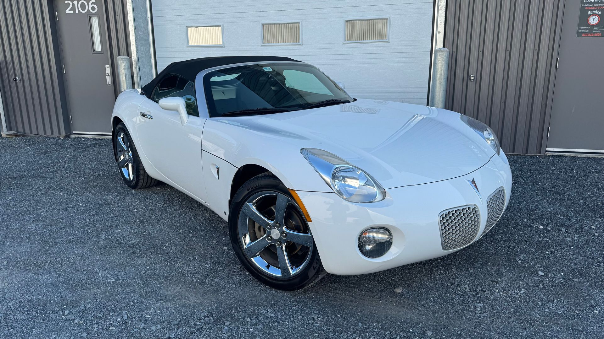 Pontiac Solstice décapotable blanche garée devant un garage.