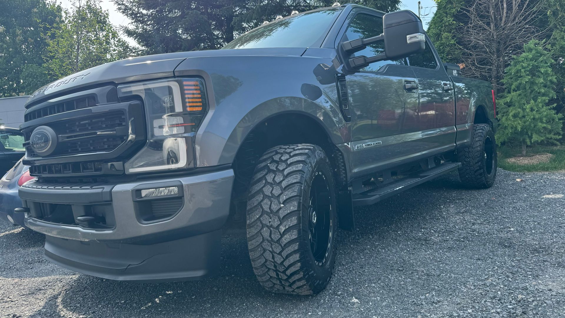 Camion Ford gris foncé garé sur du gravier, roues et pneus noirs.