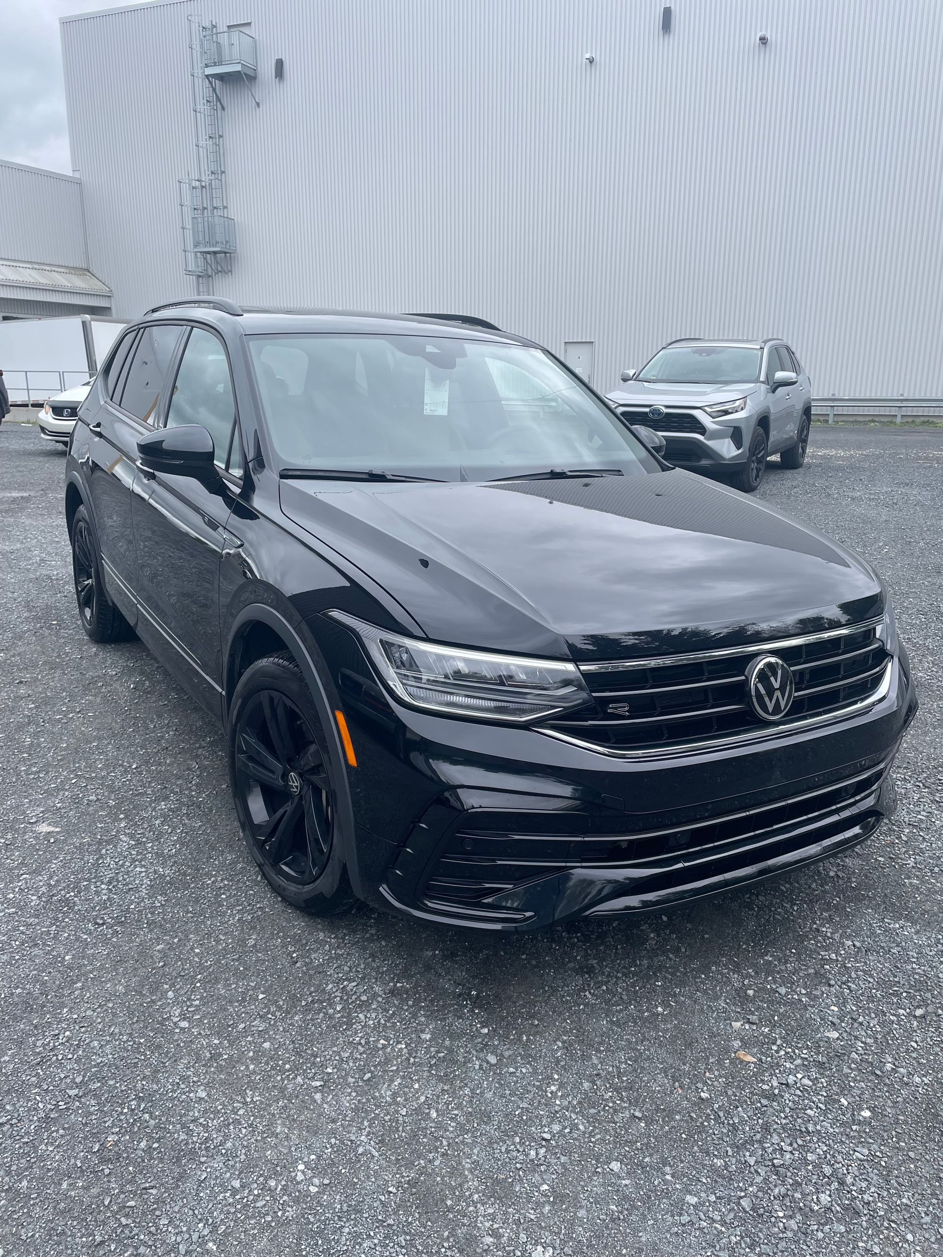 SUV Volkswagen Tiguan noir garé à l'extérieur sur du gravier.