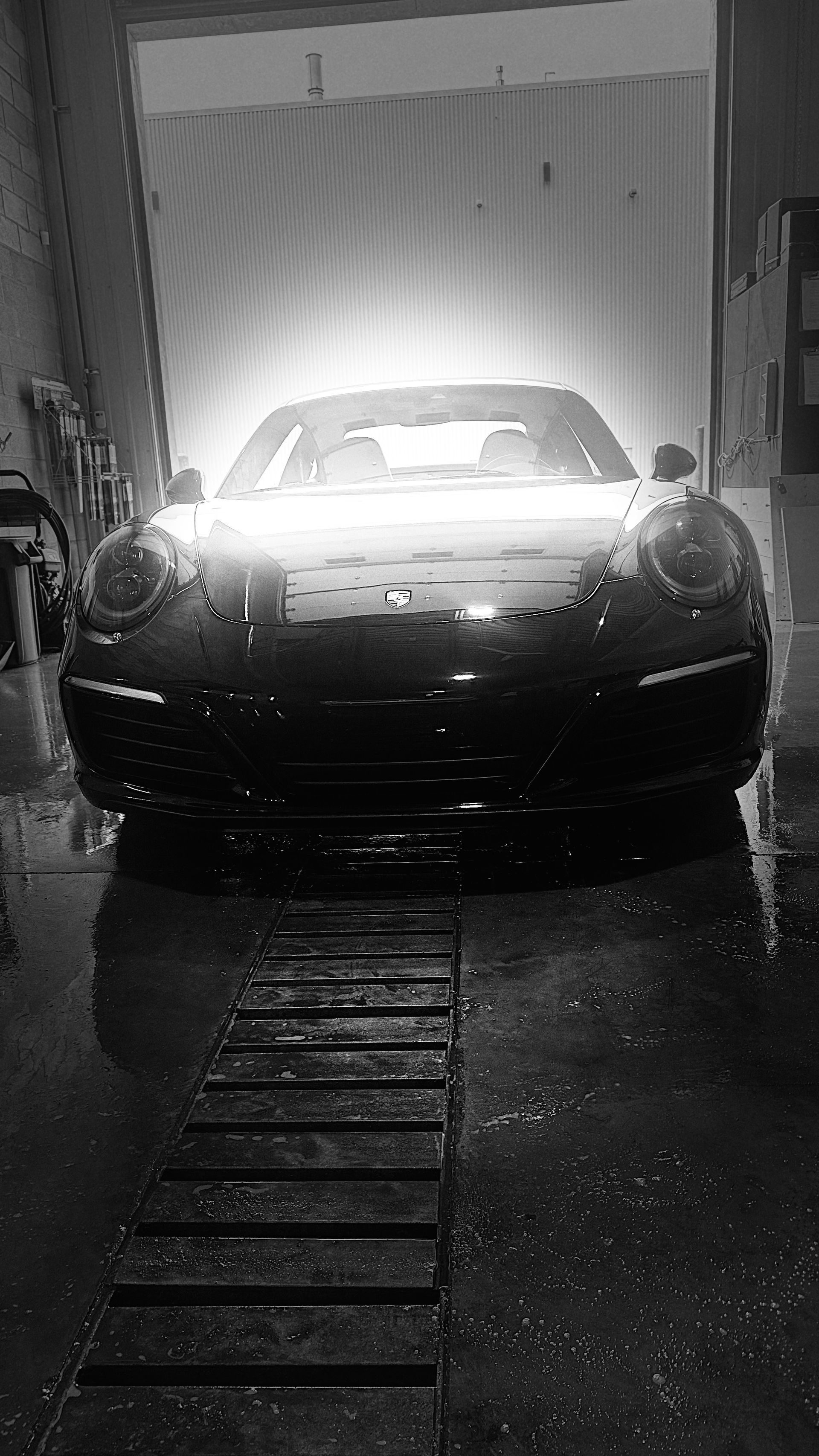 Porsche décapotable noire lavée dans une station de lavage.