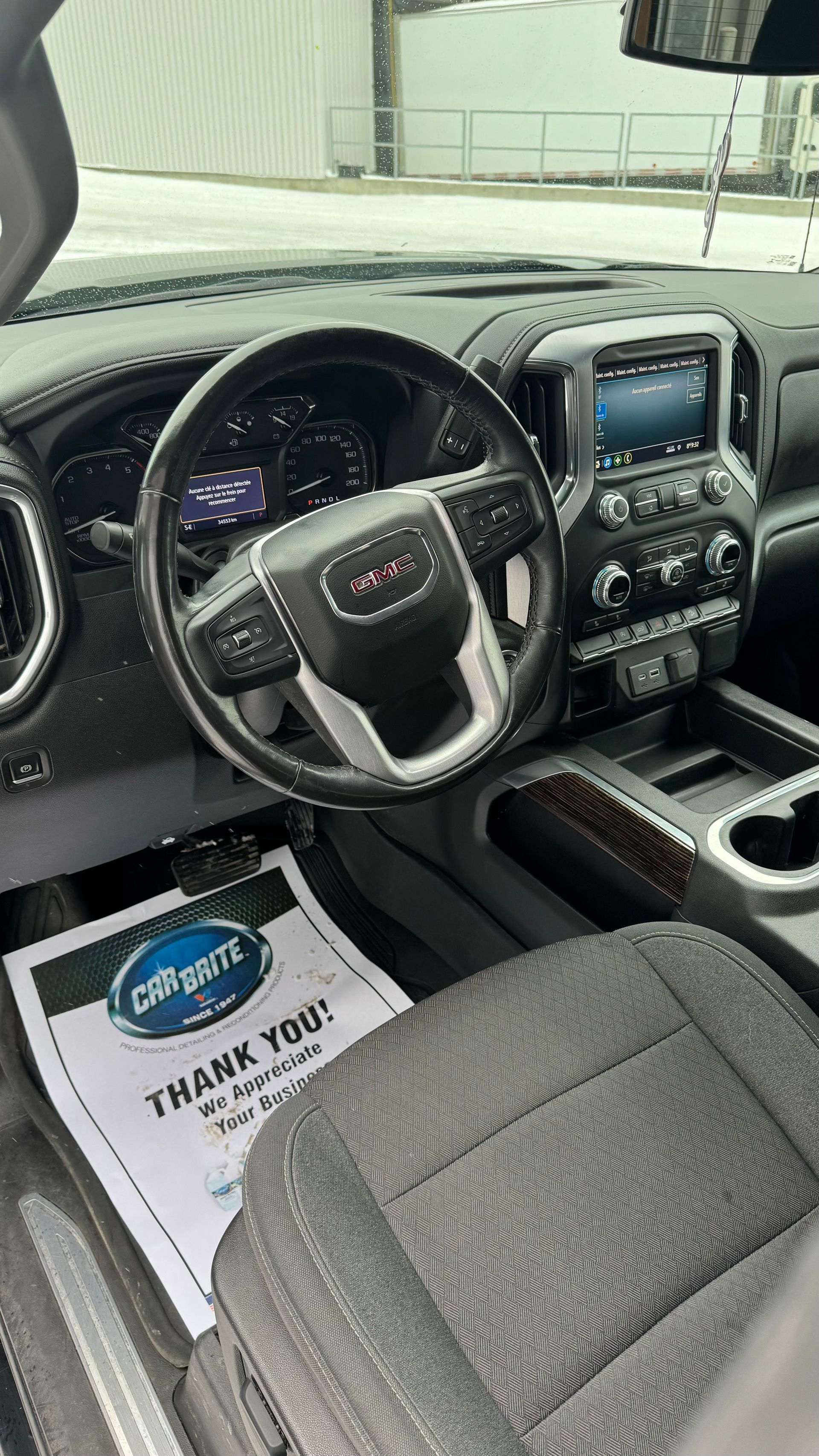 Intérieur d'un camion GMC : volant, tableau de bord, console centrale et siège conducteur avec panneau « Merci ».
