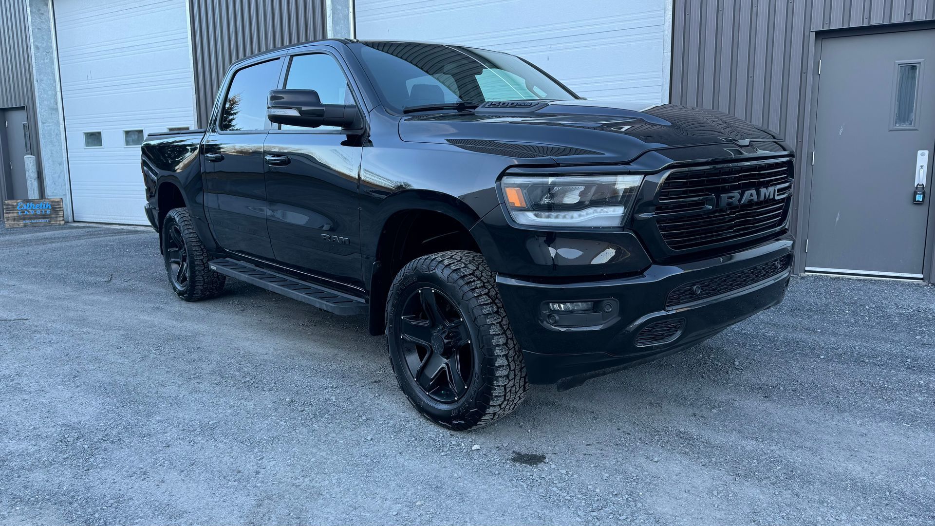 Camionnette Black Ram stationnée devant un bâtiment avec une surface en gravier gris.