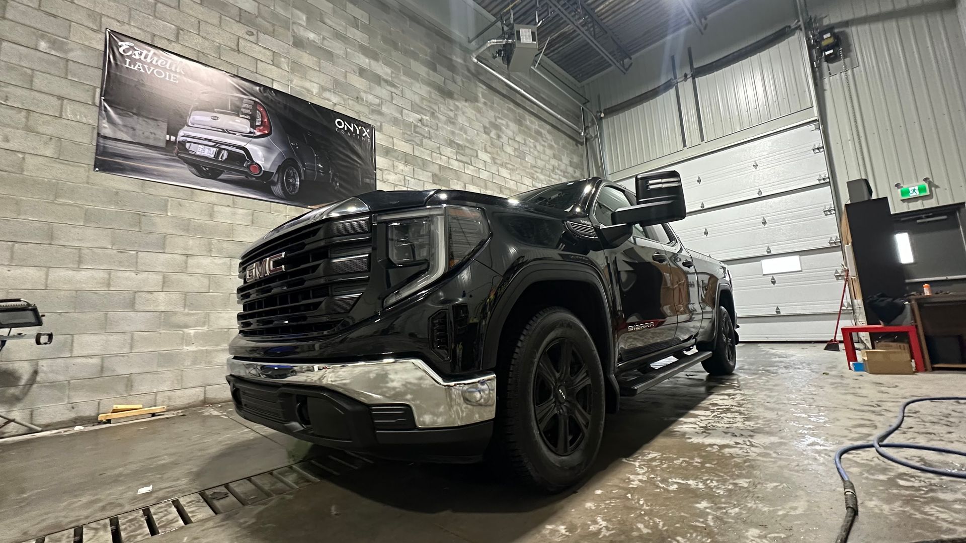 Camion GMC noir stationné à l'intérieur d'un garage; garniture chromée, roues noires.