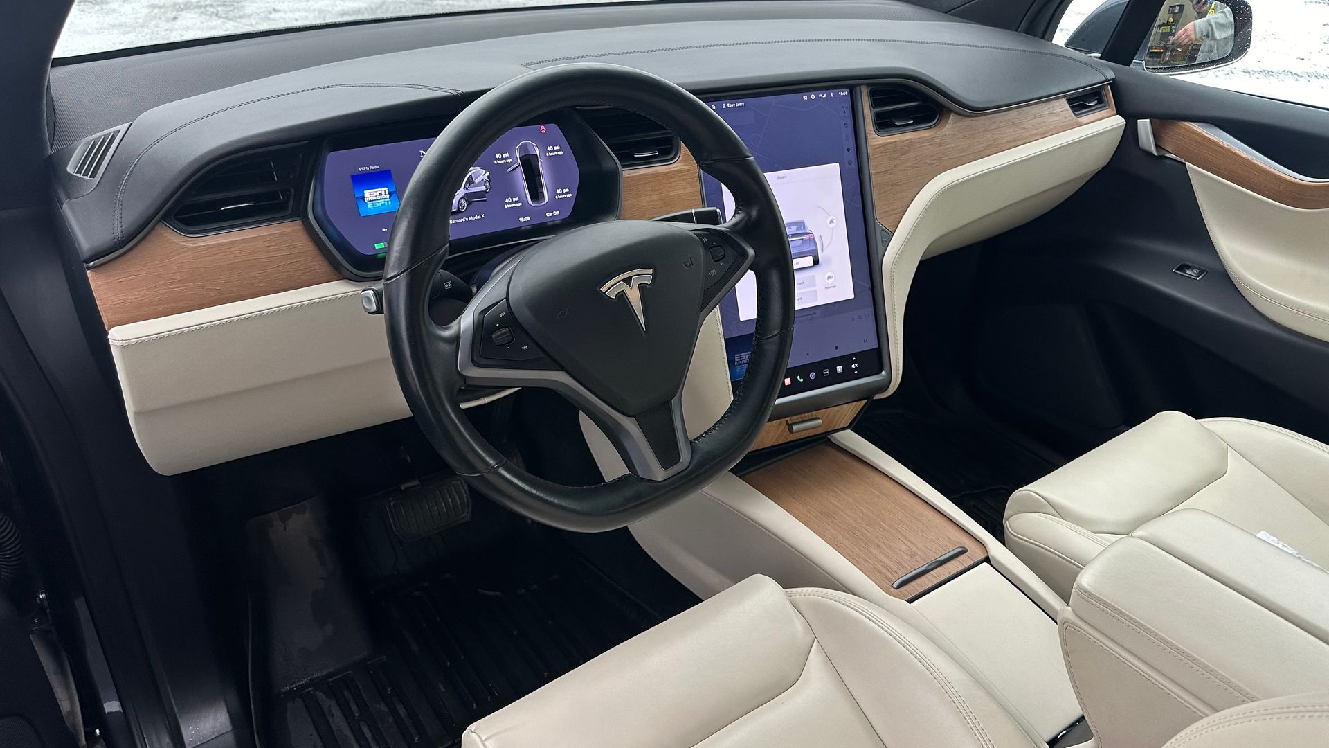 Intérieur de Tesla avec volant, tableau de bord et écran. Touches beiges et marron.