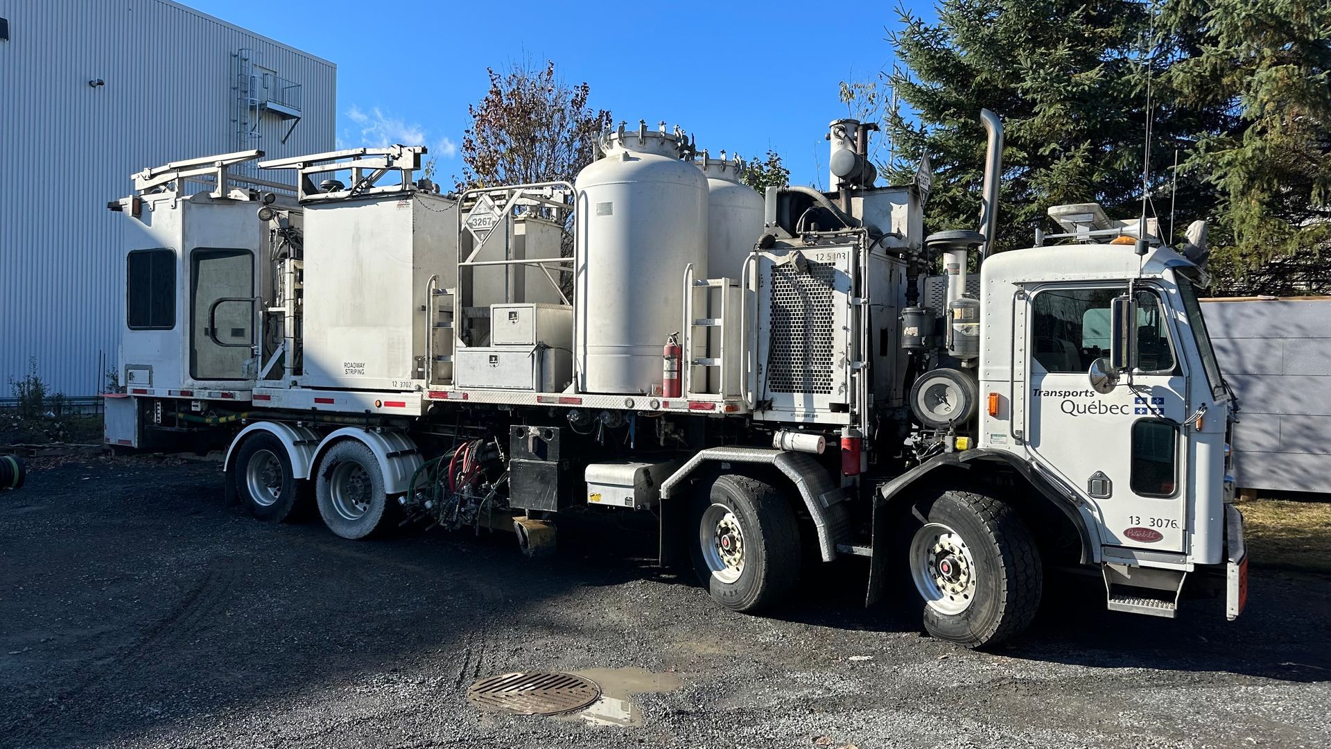 Camion blanc avec plusieurs réservoirs et machines, à l'extérieur.