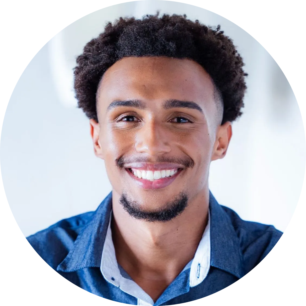 Um homem com cabelos cacheados e barba está sorrindo em um círculo.