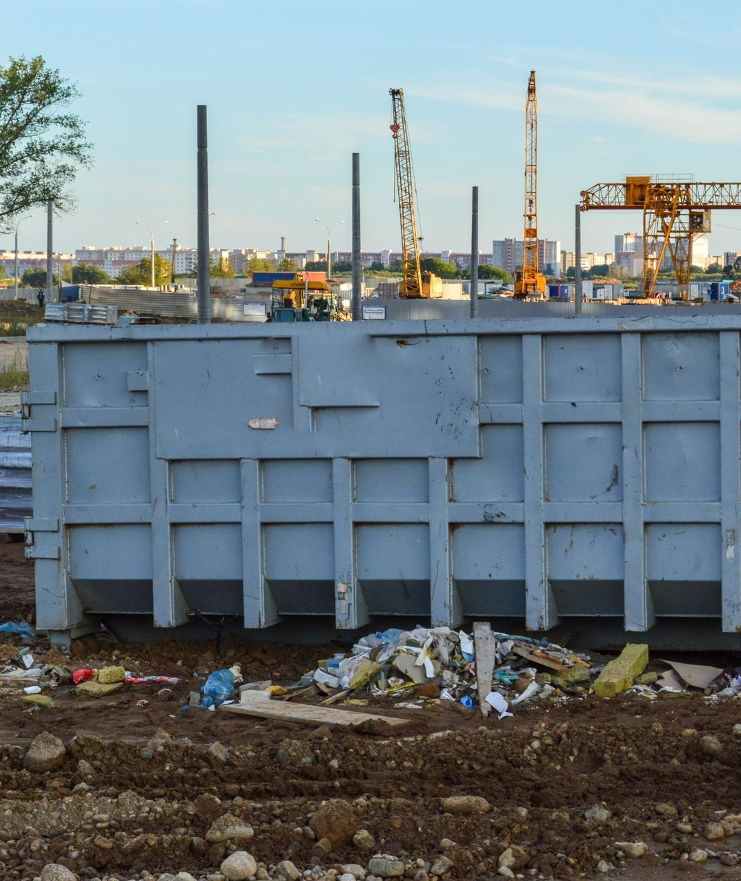 A large dumpster is sitting in the middle of a construction site.