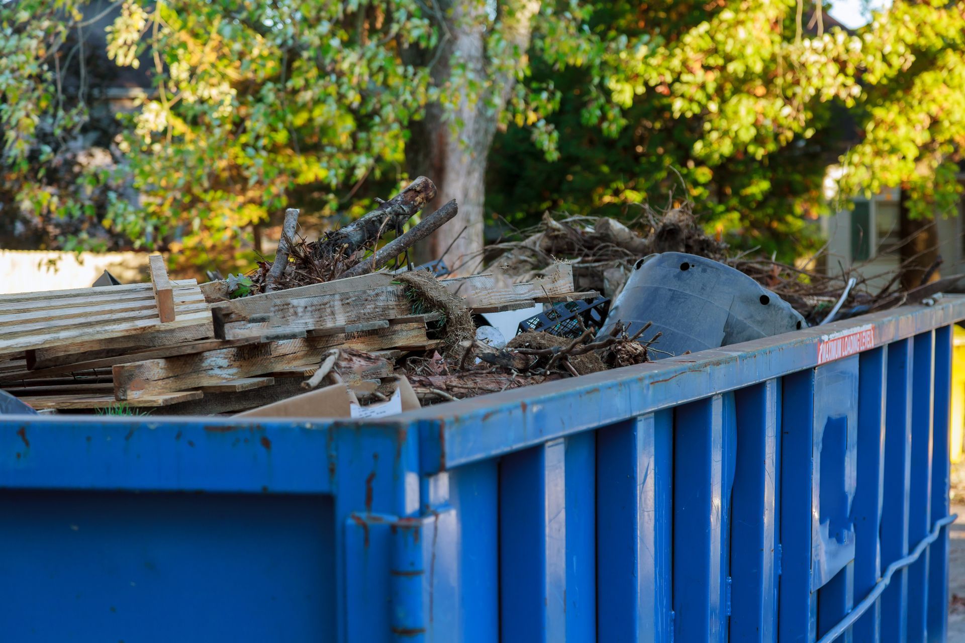 A blue dumpster filled with wood and metal.