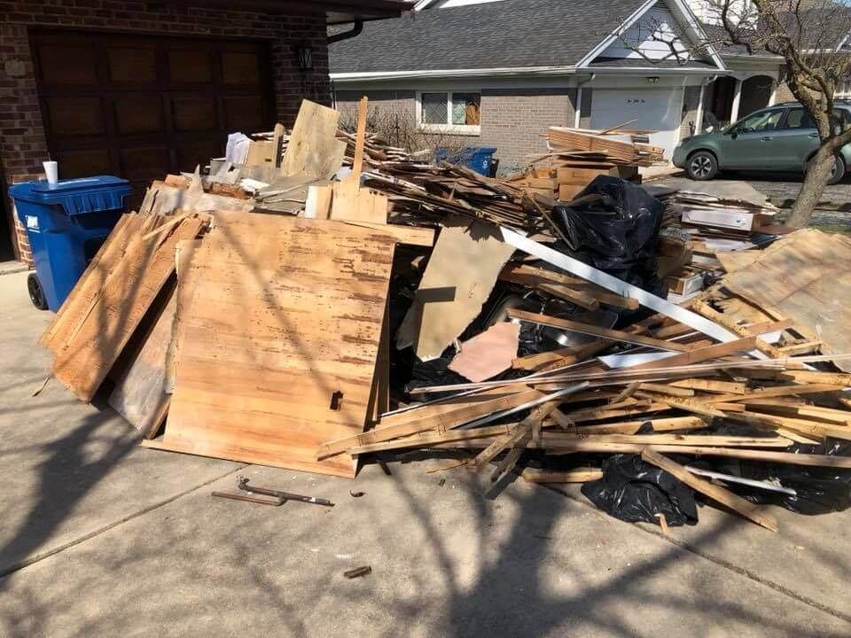 A pile of wood is sitting on the sidewalk in front of a house.