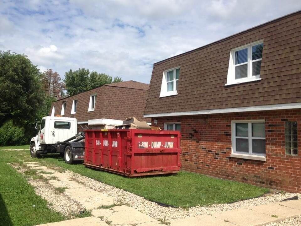 A red dumpster is parked in front of a brick building