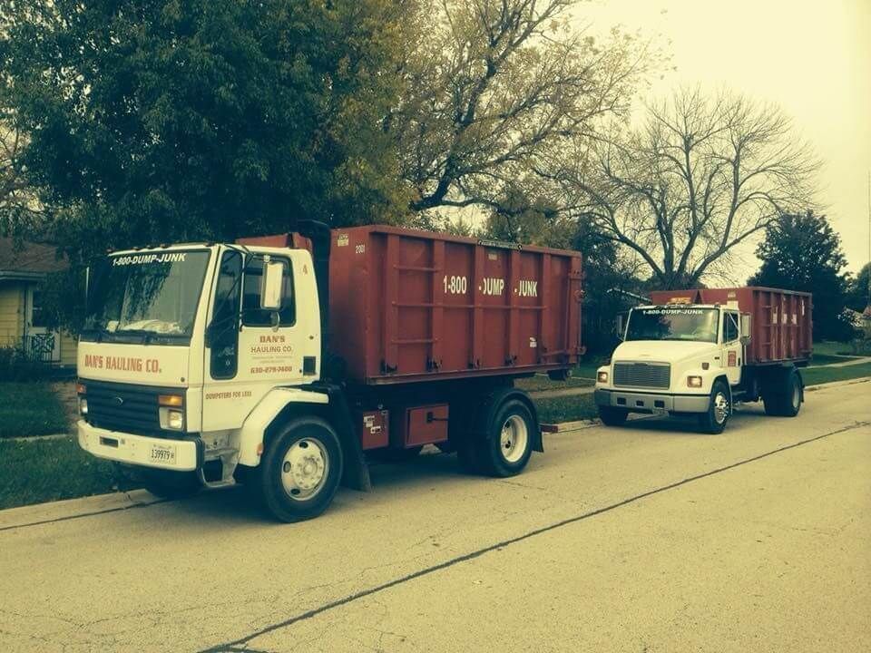 Two dump trucks are parked on the side of the road