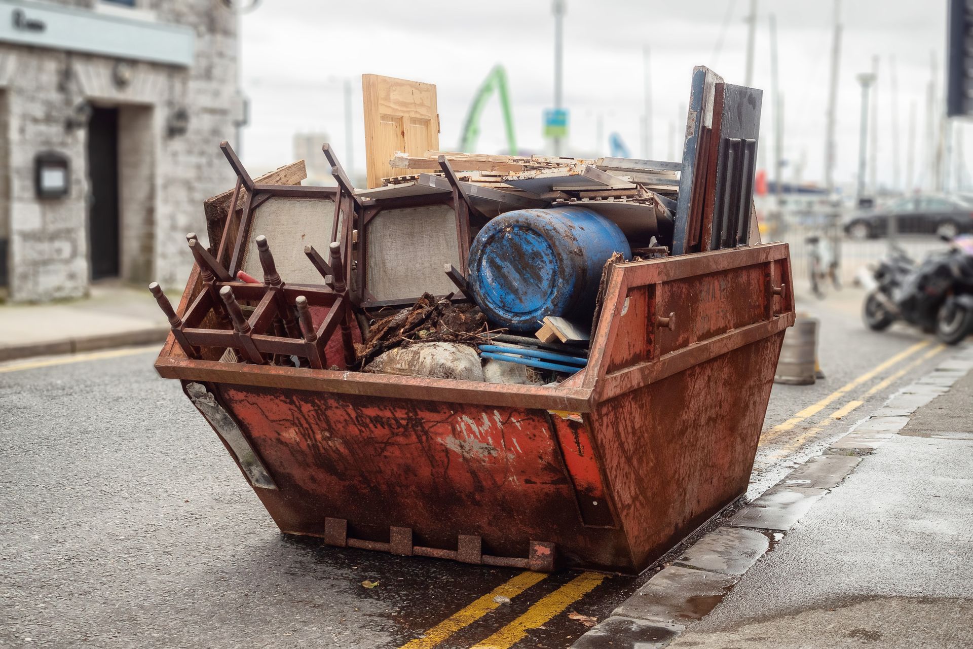 A dumpster filled with junk is parked on the side of the road.