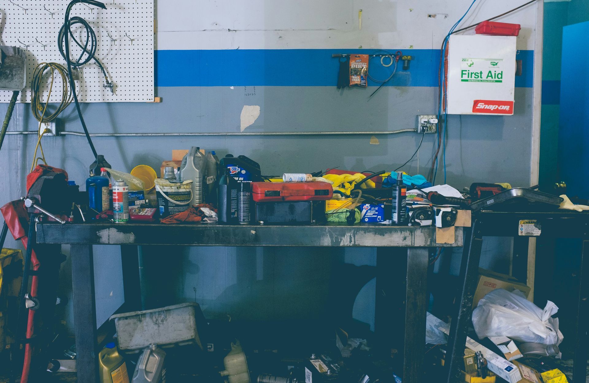 A messy workbench in a garage filled with tools.