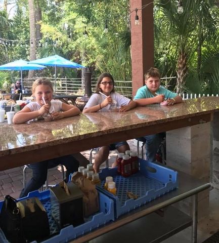 Three children are sitting at a table giving thumbs up