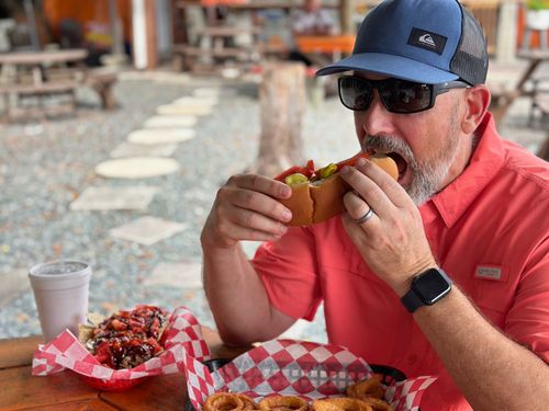 A man is sitting at a table eating a hot dog.