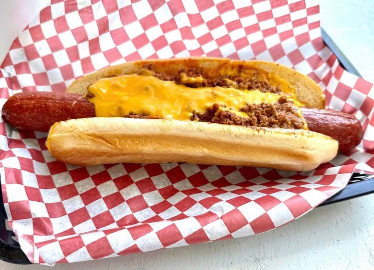 A chili cheese dog is sitting on a checkered paper