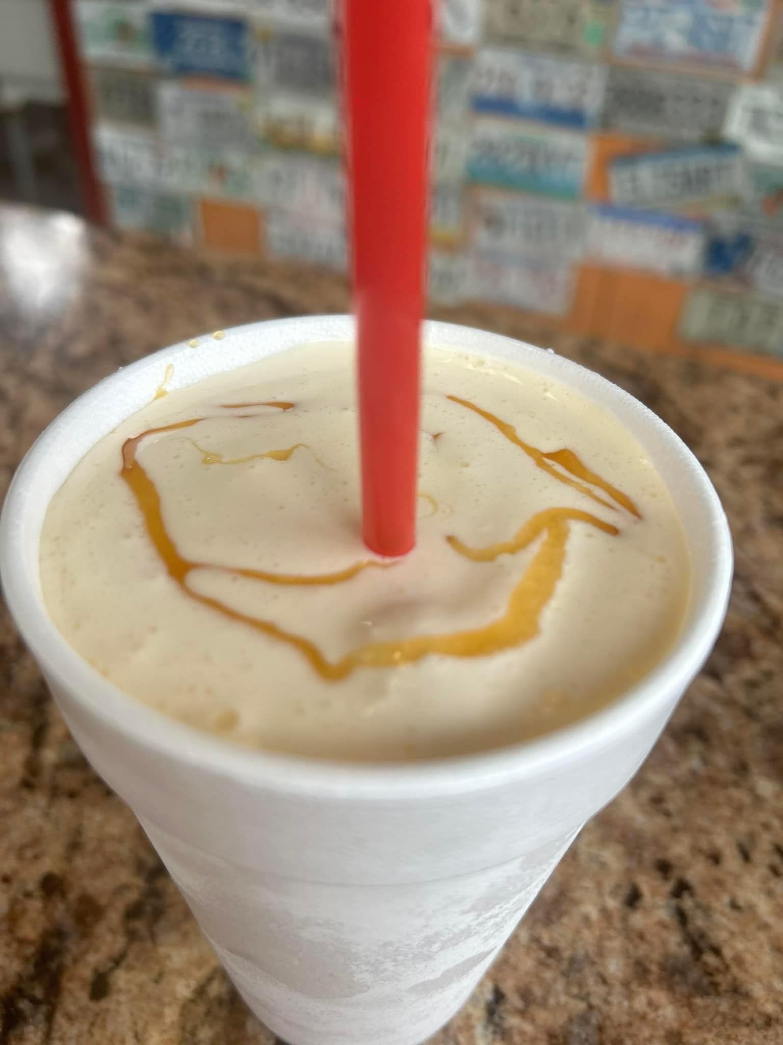 A close up of a milkshake with a straw in it on a table.