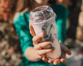 A woman is holding a cup of milkshake in her hands.